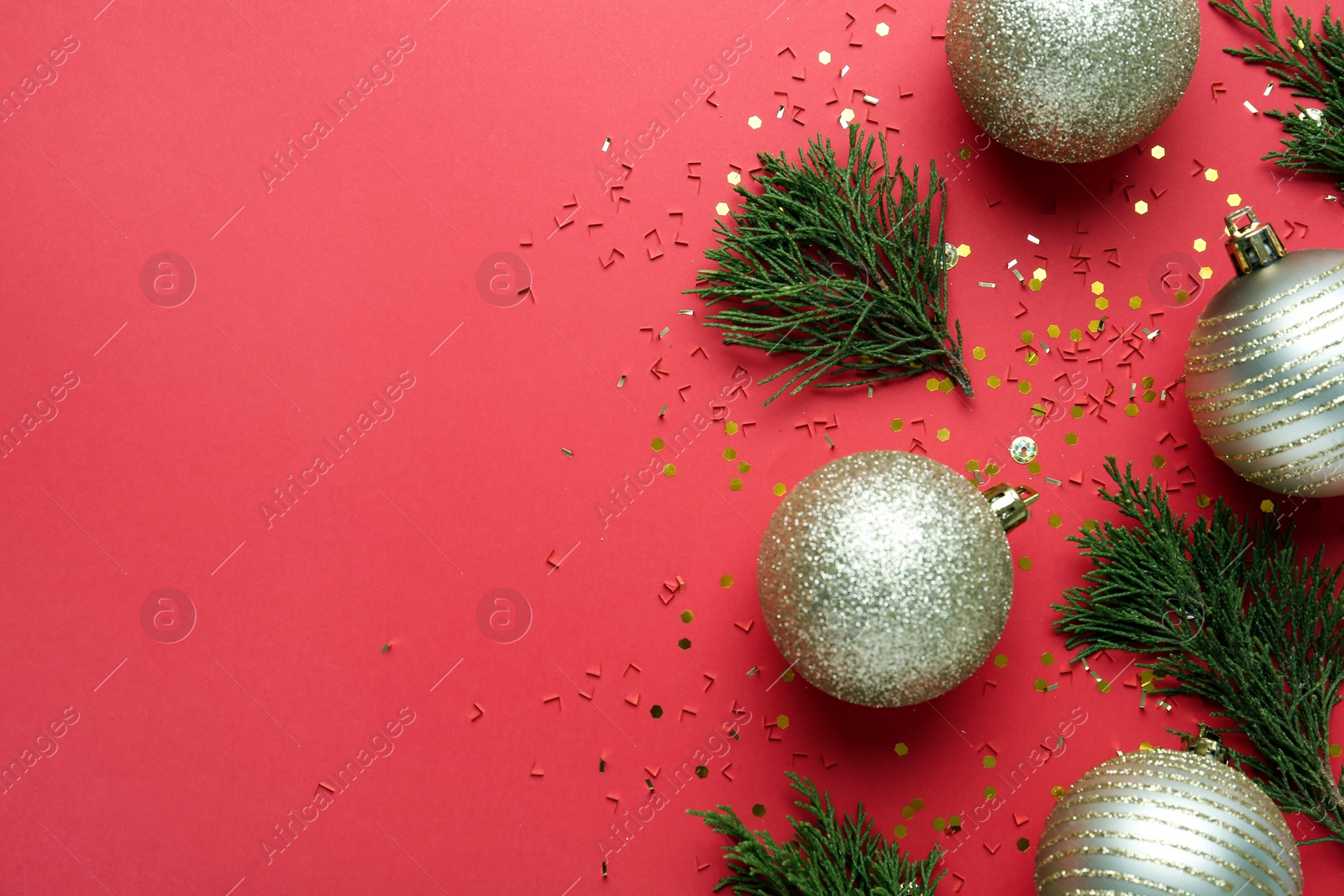 Photo of Beautiful shiny Christmas balls and fir branches on red background, flat lay. Space for text