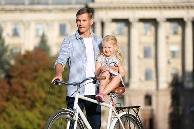 Happy father and his daughter with bicycle outdoors on sunny day