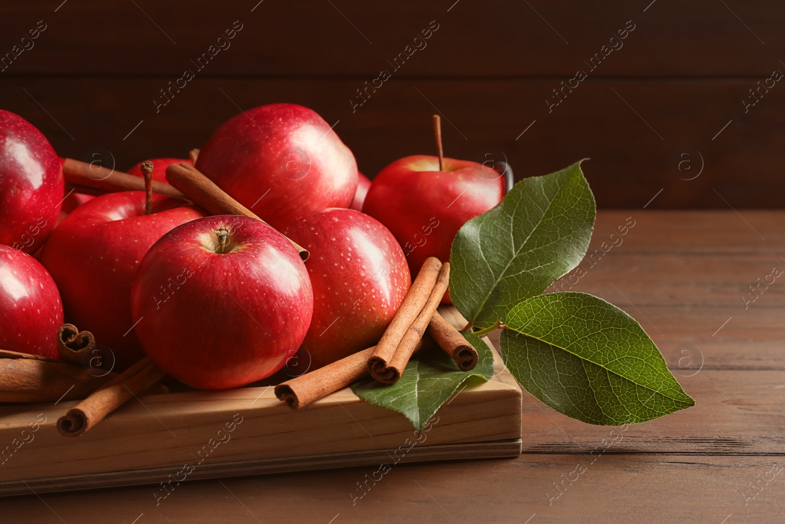 Photo of Fresh apples and cinnamon sticks on wooden table