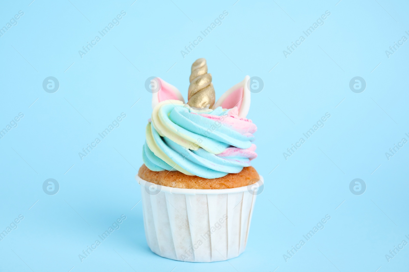 Photo of Cute sweet unicorn cupcake on light blue background