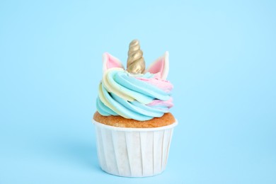 Photo of Cute sweet unicorn cupcake on light blue background