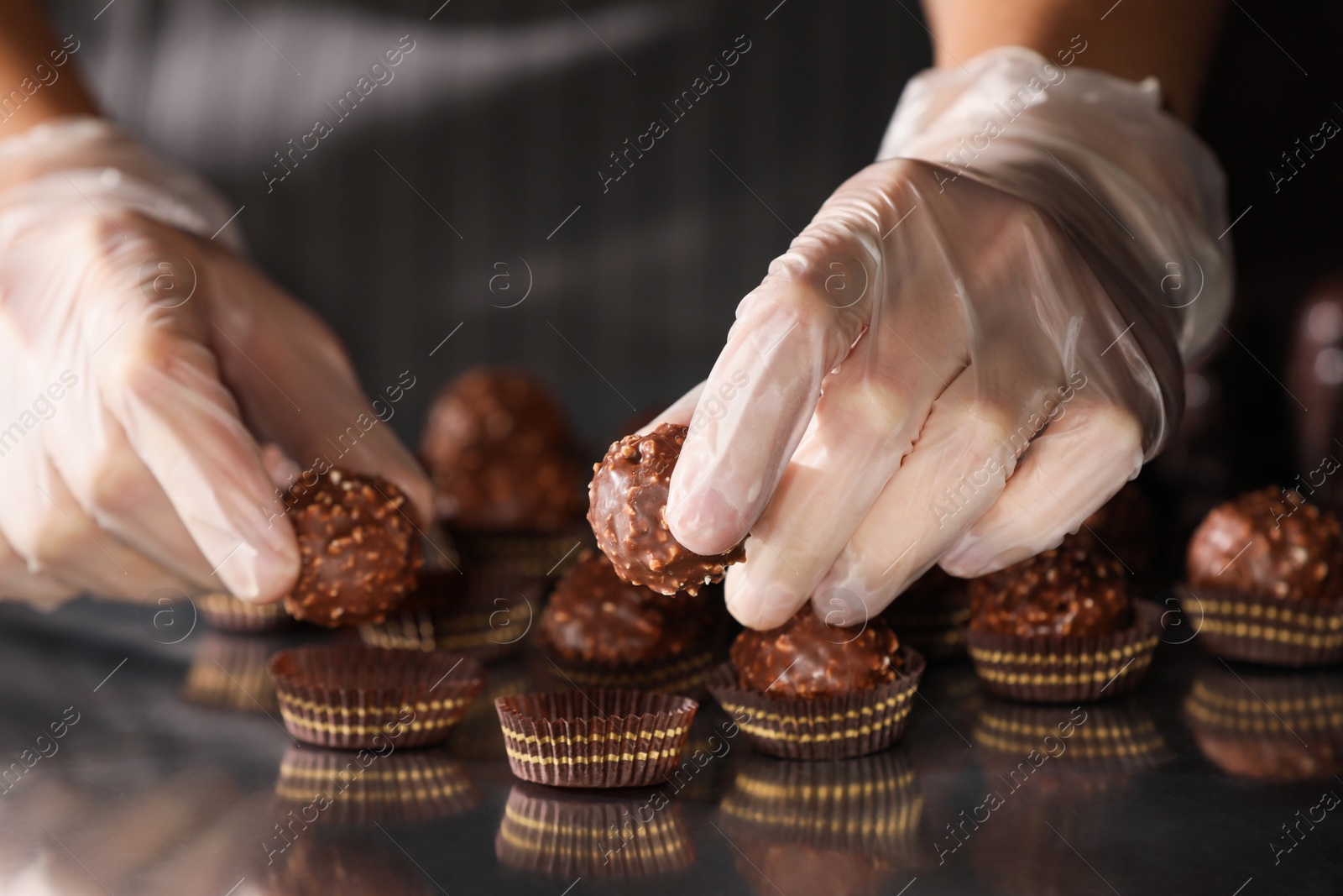 Photo of Woman packing delicious candies at production line, closeup