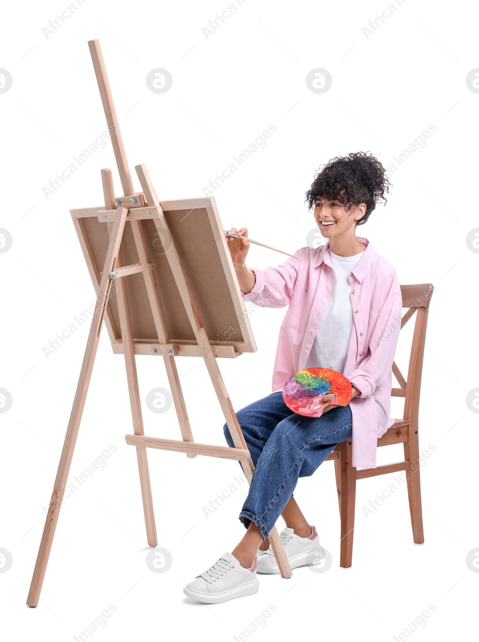 Photo of Young woman painting on easel with canvas against white background