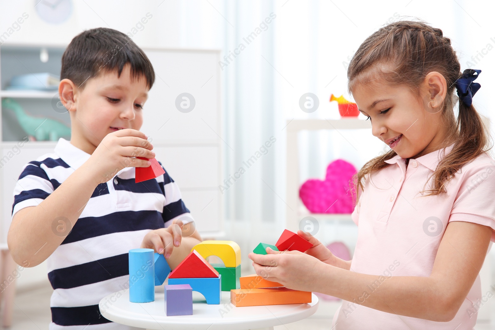 Photo of Cute children playing with colorful blocks at home