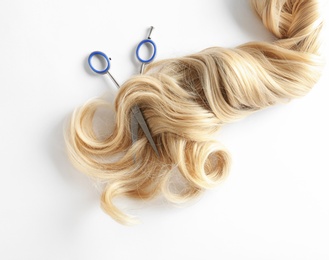 Photo of Beautiful curly blonde hair and scissors on white background, top view. Hairdresser service
