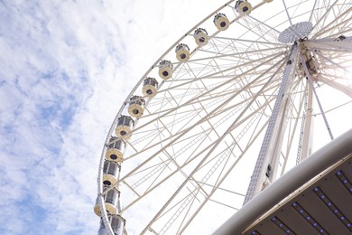 Beautiful Ferris wheel against cloudy sky, low angle view