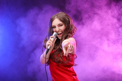 Photo of Beautiful woman with microphone singing in color lights