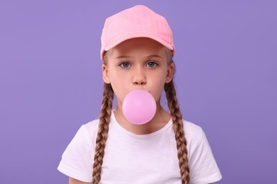 Photo of Girl blowing bubble gum on purple background