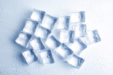 Ice cubes with water drops on white background, top view