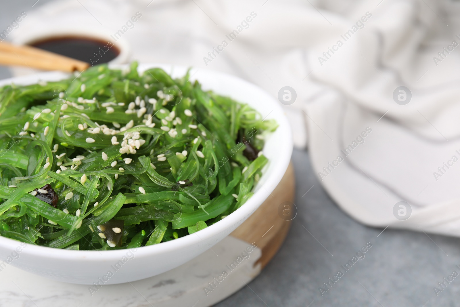 Photo of Tasty seaweed salad in bowl on gray table, closeup