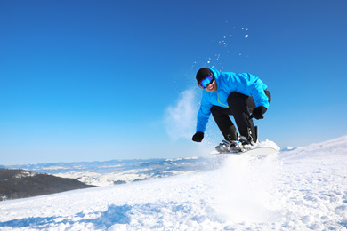 Photo of Man snowboarding on snowy hill, space for text. Winter vacation