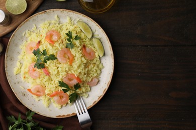 Photo of Delicious risotto with shrimps, lime and parsley served on wooden table, flat lay. Space for text