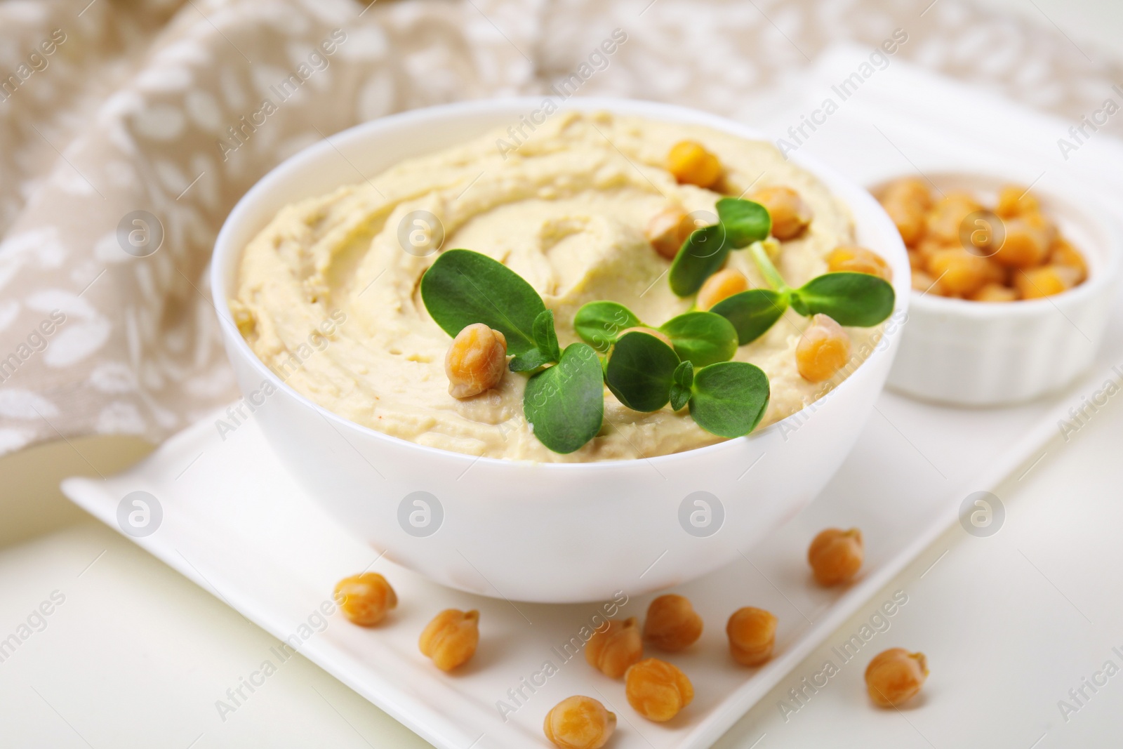 Photo of Delicious hummus with chickpeas served on white table, closeup