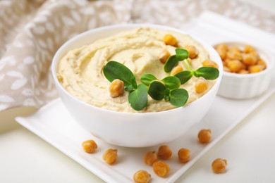 Photo of Delicious hummus with chickpeas served on white table, closeup