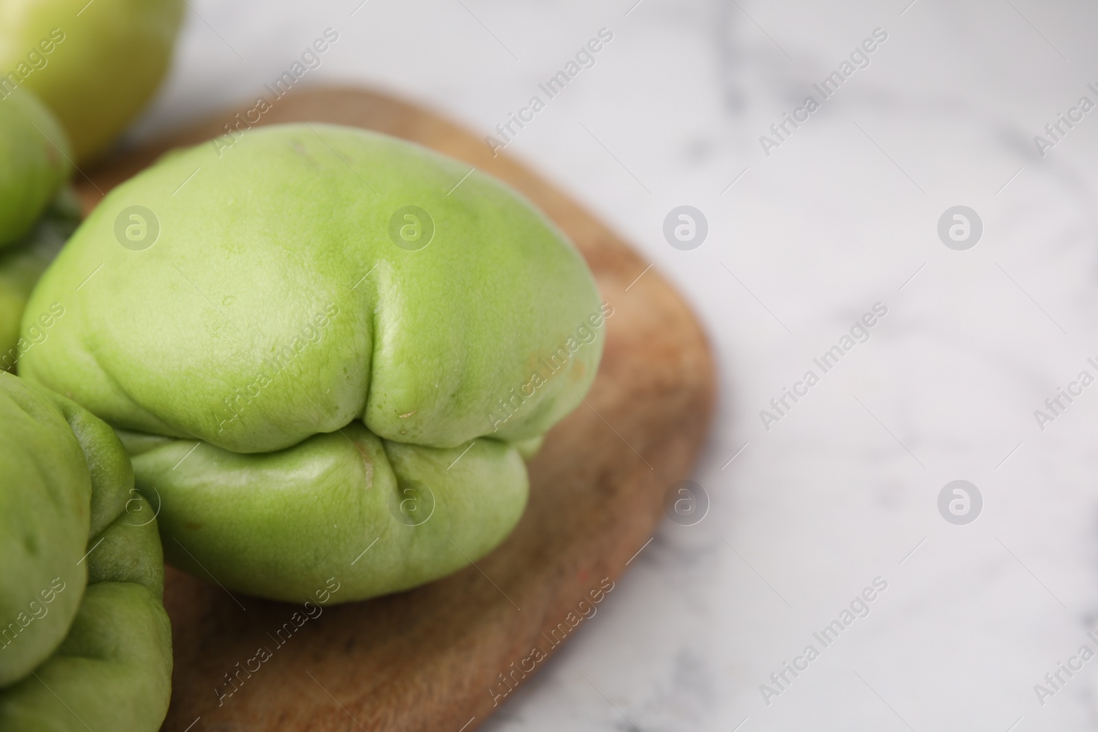 Photo of Fresh green chayote on light table, closeup. Space for text