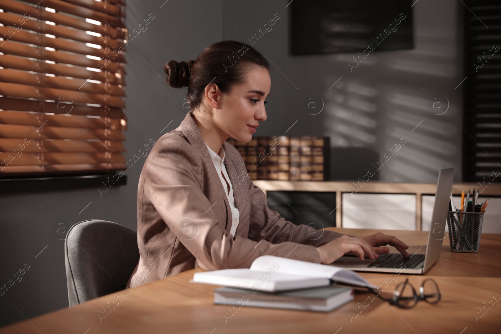 Photo of Woman working with laptop at wooden desk in office