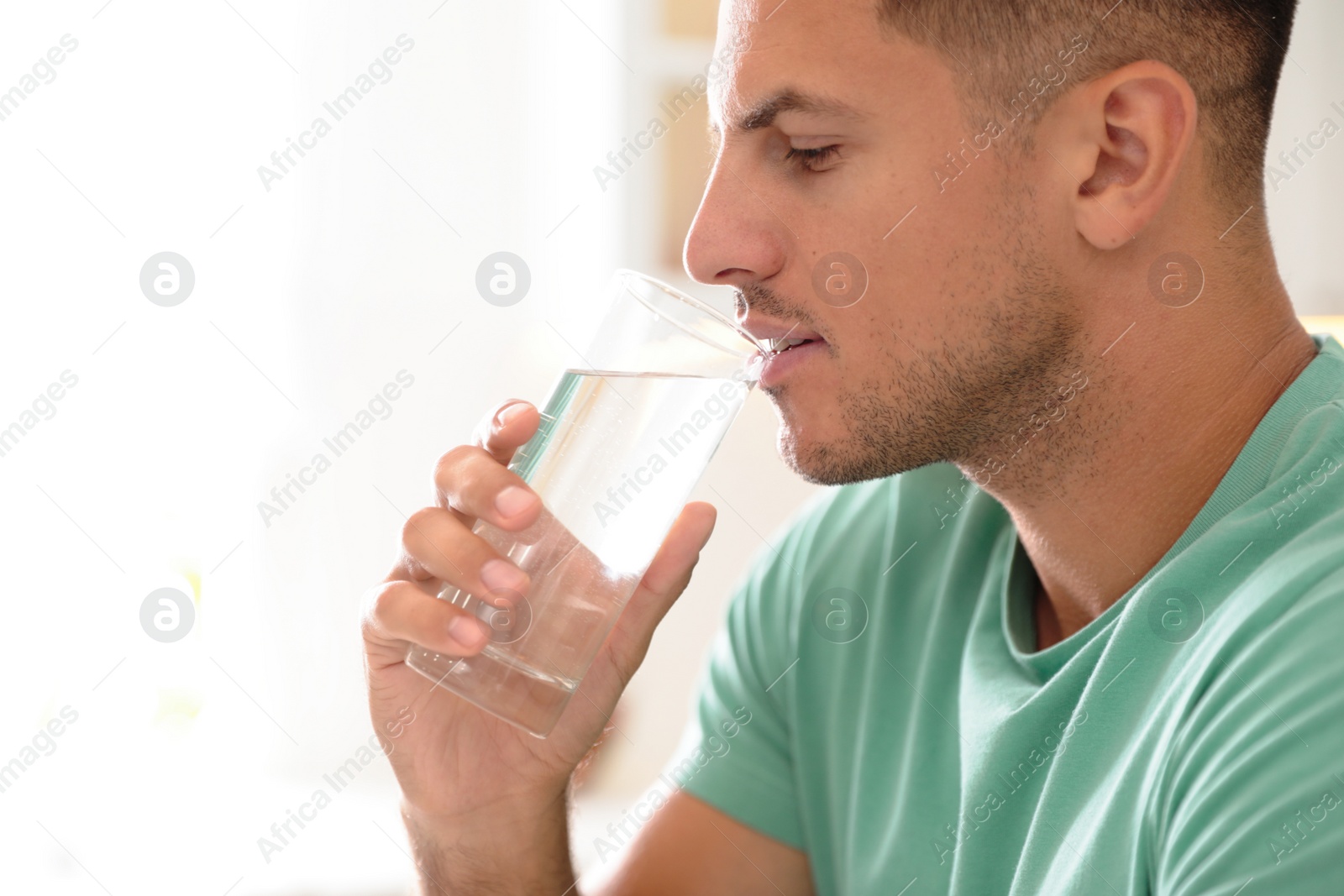 Photo of Man drinking pure water from glass indoors, closeup