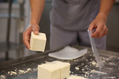 Worker packaging feta cheese at modern factory, closeup