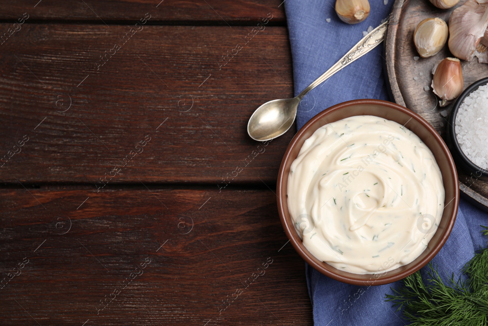 Photo of Tasty creamy dill sauce and ingredients on wooden table, flat lay. Space for text