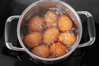 Chicken eggs boiling in pot on electric stove, top view
