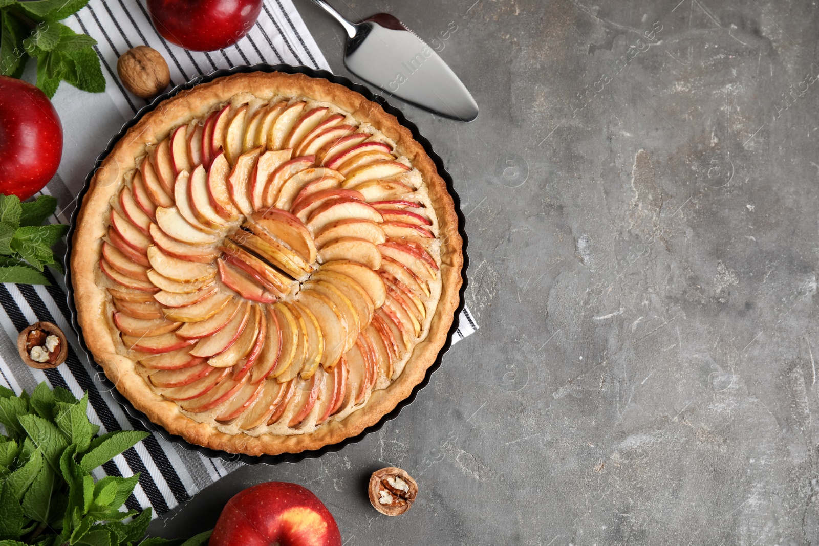 Photo of Flat lay composition with delicious homemade apple tart on grey table. Space for text