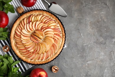 Flat lay composition with delicious homemade apple tart on grey table. Space for text