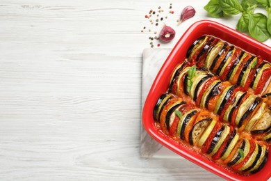 Delicious ratatouille in baking dish on white wooden table, flat lay. Space for text