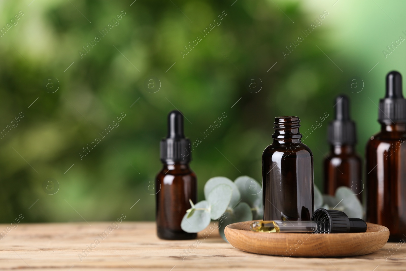 Photo of Bottles of essential oil on wooden table. Space for text