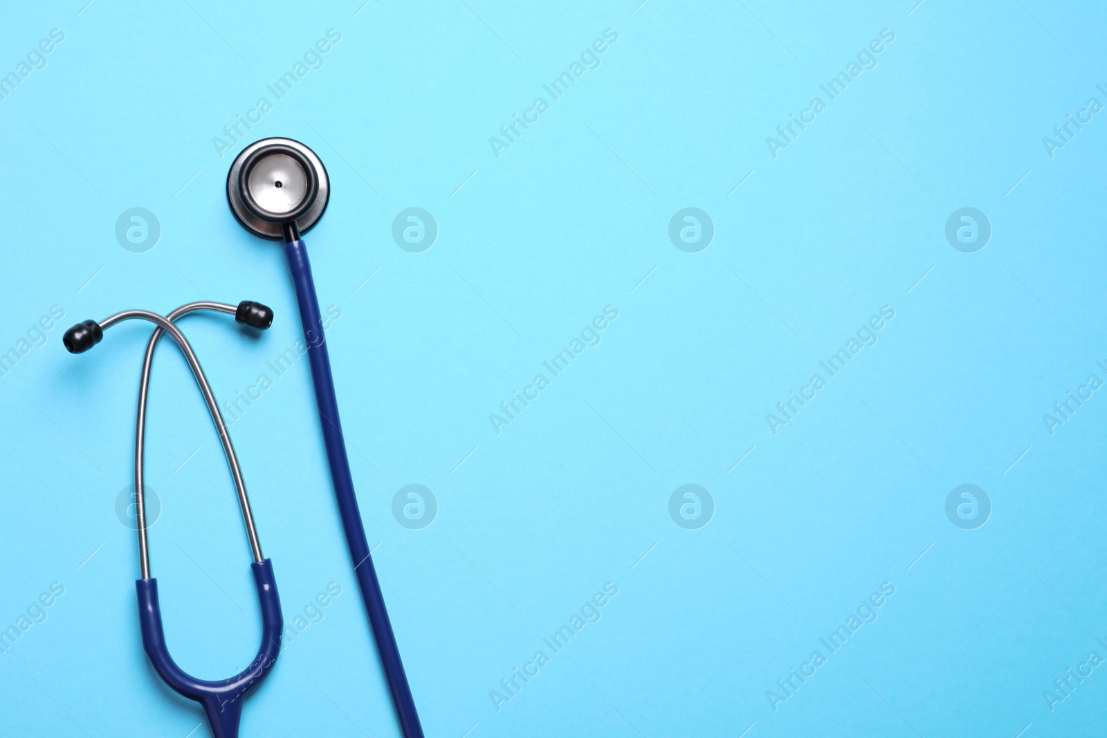 Photo of Stethoscope on light blue background, top view. Space for text
