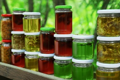 Photo of Different types of honey in jars on wooden table outdoors