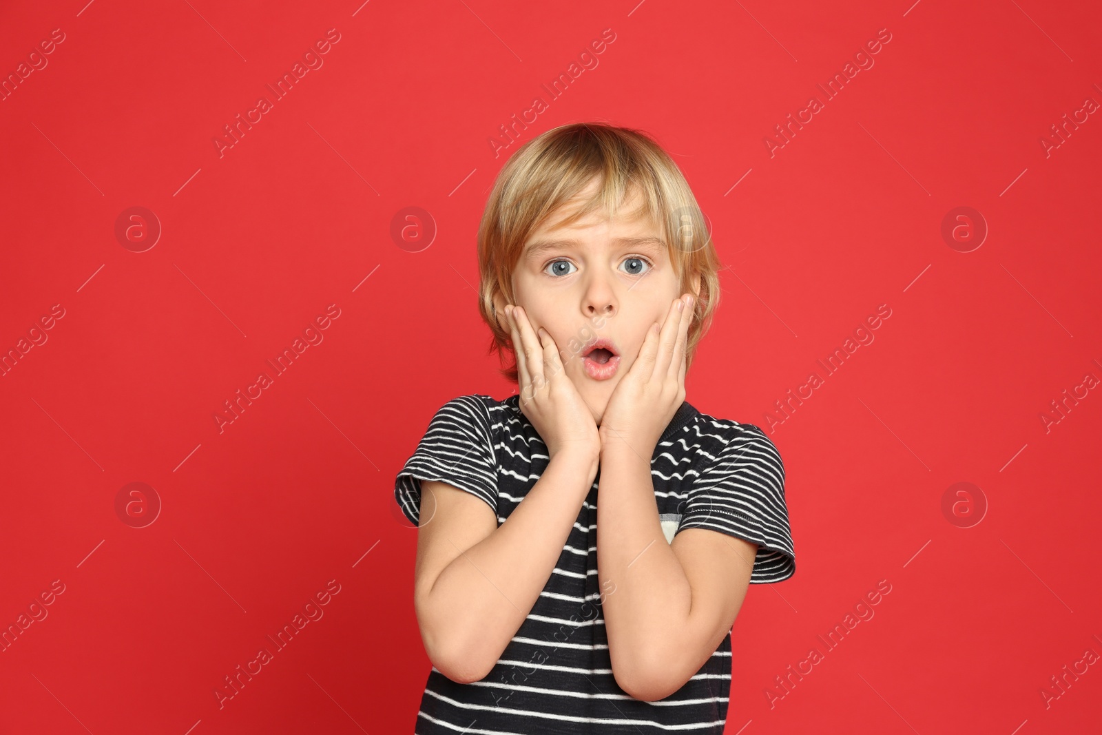 Photo of Portrait of emotional little boy on red background