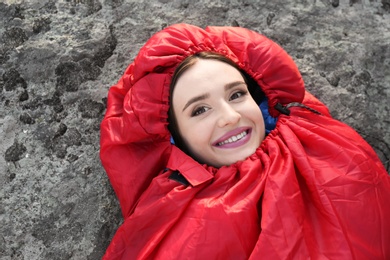 Young woman lying in red sleeping bag outdoors