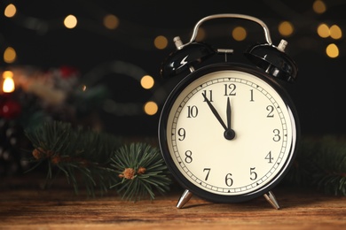 Photo of Vintage alarm clock and decor on wooden table against blurred Christmas lights, closeup. New Year countdown