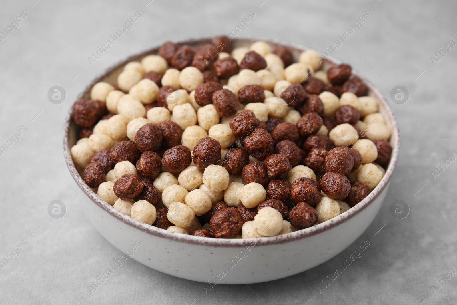 Photo of Tasty cereal balls in bowl on grey table, closeup