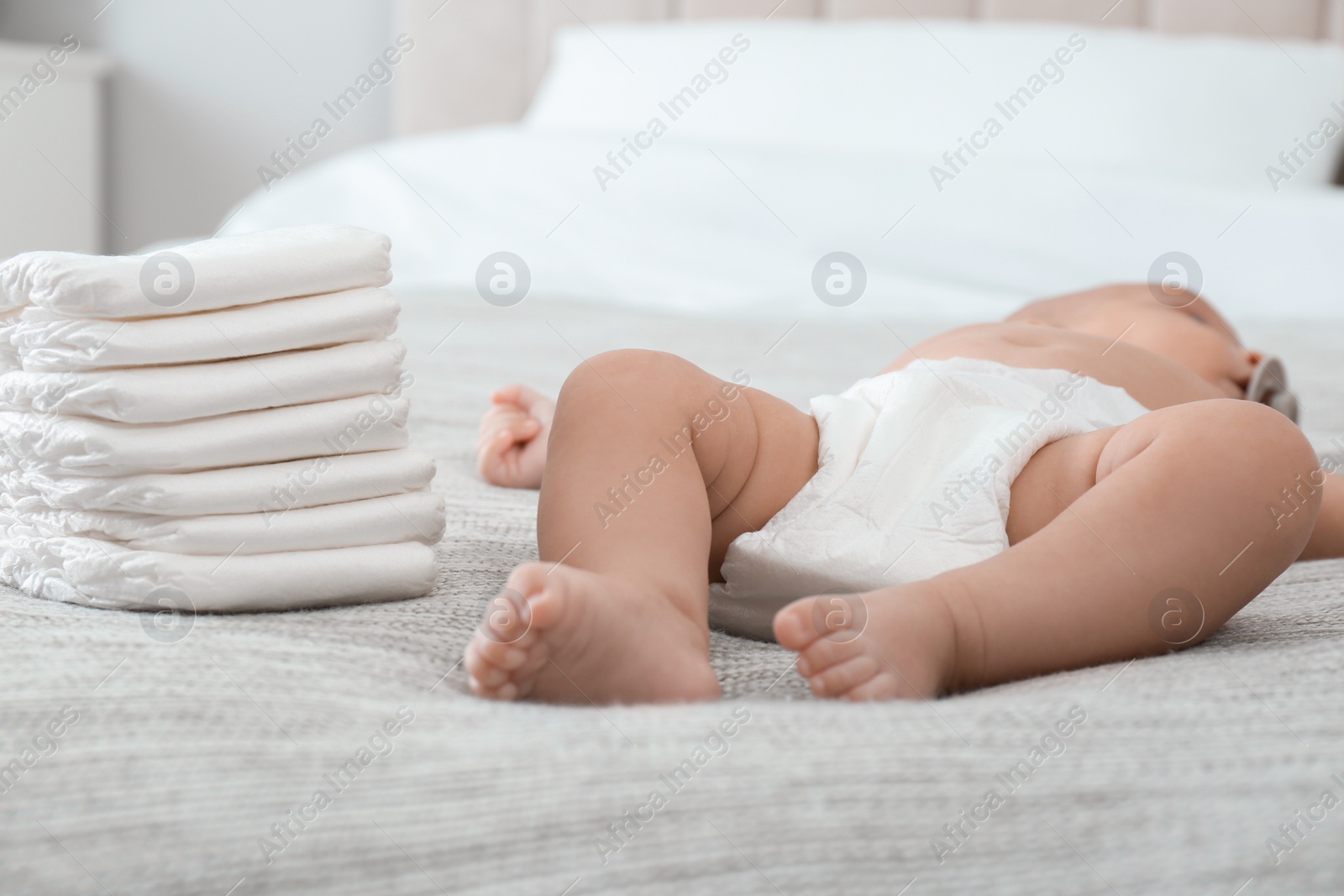 Photo of Cute little baby in diaper on bed at home