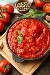 Photo of Homemade tomato sauce in bowl and ingredients on wooden table, above view