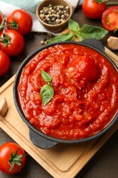 Homemade tomato sauce in bowl and ingredients on wooden table, above view