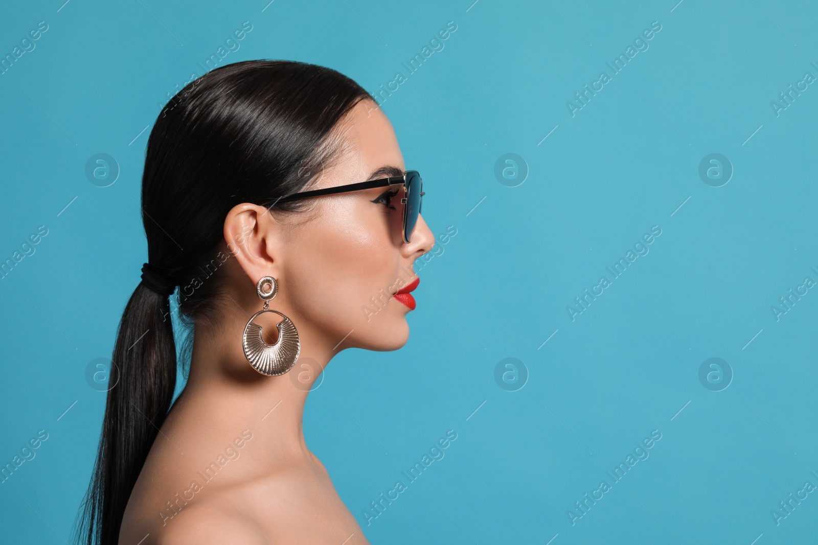 Photo of Attractive woman in fashionable sunglasses against light blue background. Space for text