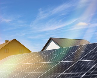 Photo of Solar panels near houses under blue sky on sunny day. Alternative energy source