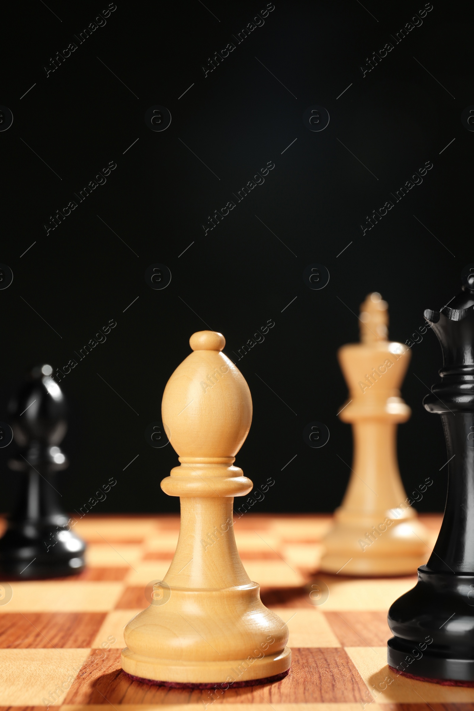 Photo of Different game pieces on chessboard against dark background, space for text