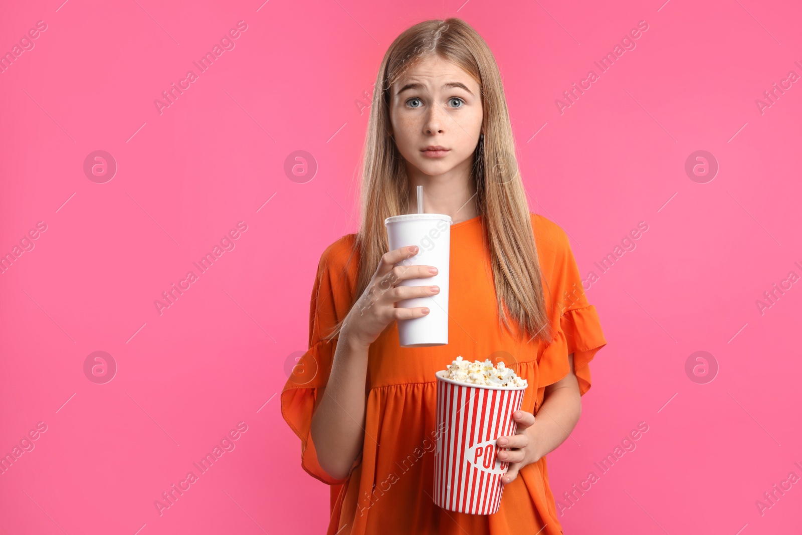 Photo of Emotional teenage girl with popcorn and beverage during cinema show on color background