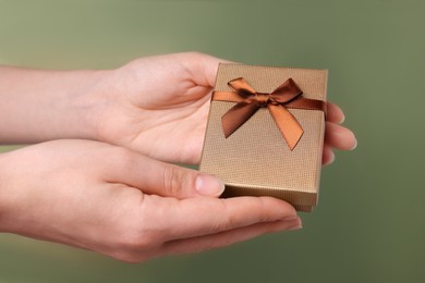 Photo of Doctor holding gift box on olive background, closeup. Medical present