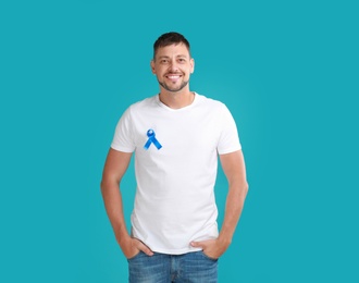 Man with blue ribbon on turquoise background. Urology cancer awareness