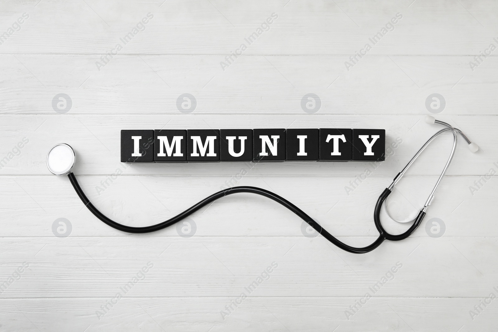Photo of Black cubes with word Immunity and stethoscope on white wooden table, flat lay
