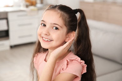 Little girl with hearing aid at home