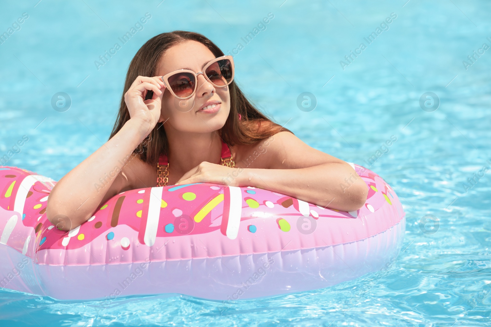 Photo of Beautiful young woman on inflatable ring in swimming pool