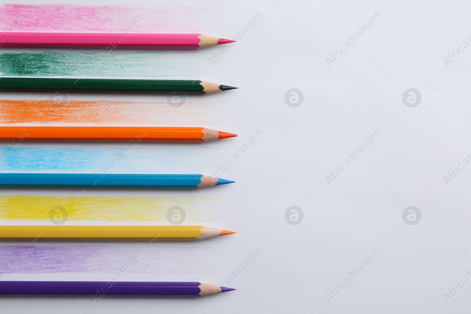 Photo of Colorful pencils with swatches on white background, top view