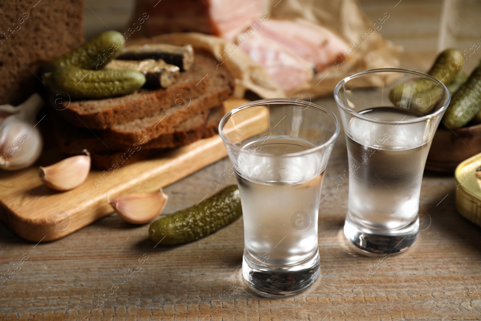 Photo of Cold Russian vodka with snacks on wooden table, closeup