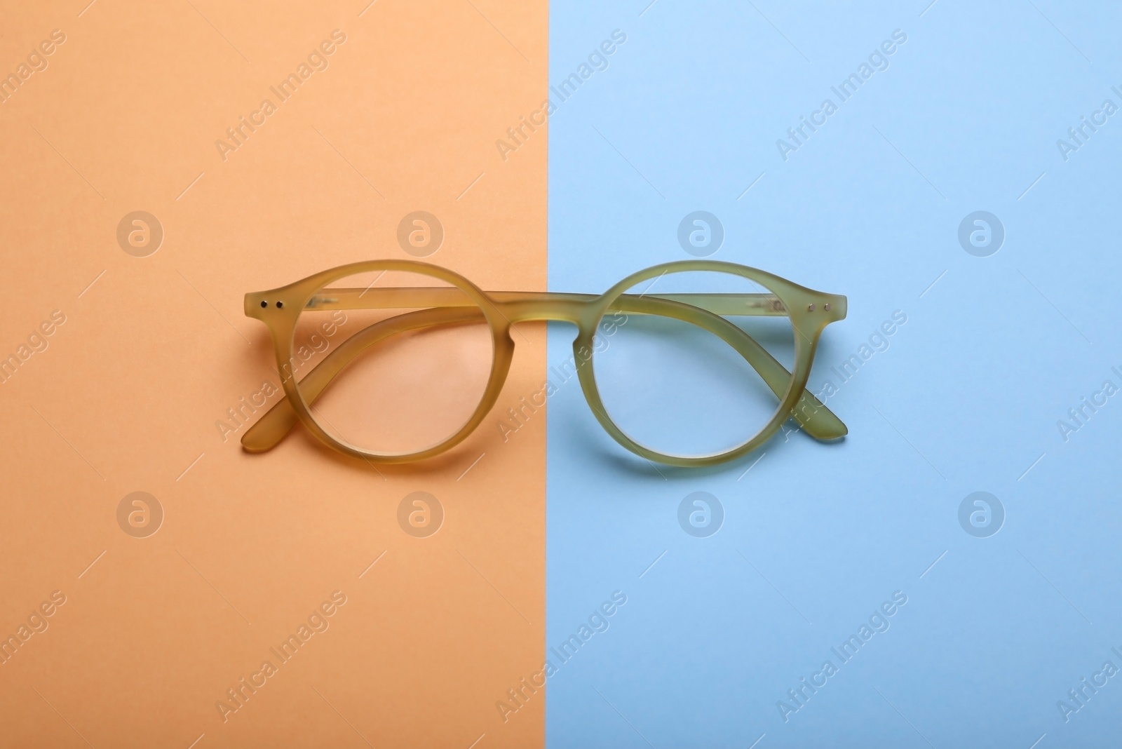 Photo of Glasses with corrective lenses on color background, top view