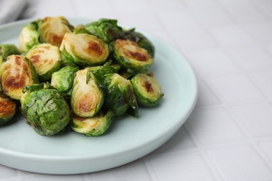 Delicious roasted Brussels sprouts on white tiled table, closeup